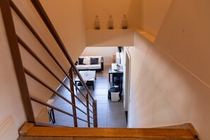 A staircase leading to a living area with a sofa, a small table, and a coffee machine. - Duplex Stay at the Alfonsine Farm (Heers)