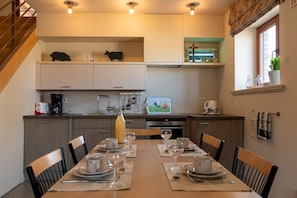 A modern kitchen with a dining area, equipped with a coffee machine, a TV, and a window with a view. - Duplex Stay at the Alfonsine Farm (Heers)