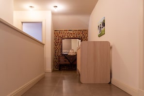 A hallway with a wooden door, a brick wall, and a picture on the wall. - Duplex Stay at the Alfonsine Farm (Heers)