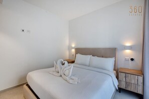 A hotel room with a bed, two wall-mounted lights, a nightstand, and a wall-mounted outlet. - Official Mercury Suites: Designer 1BR w/Balcony (St. Julian`s)