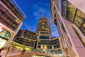 A modern multi-story building with a curved facade, large windows, and a prominent entrance. - Official Mercury Suites: Designer 1BR w/Balcony (St. Julian`s)
