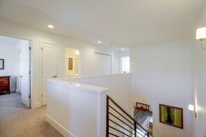 Eine Treppe mit Geländer, eine Zwischenebene mit einer Lampe und eine Tür zu einem anderen Raum.