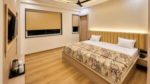Un dormitorio moderno con una cama grande, ventilador de techo, iluminación empotrada y un televisor sobre una estantería de madera.