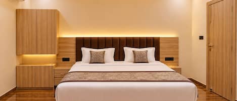 A modern bedroom with a large bed, a ceiling fan, recessed lighting, and wooden furniture.