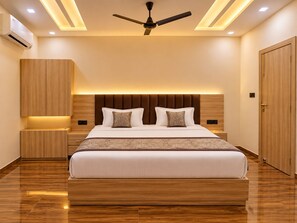 A modern bedroom with a large bed, a ceiling fan, recessed lighting, and wooden furniture. - Hotel Akrati Inn Vrindavan (Mathura)