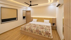 Un dormitorio moderno con cama, ventilador de techo, aire acondicionado y piso de madera.