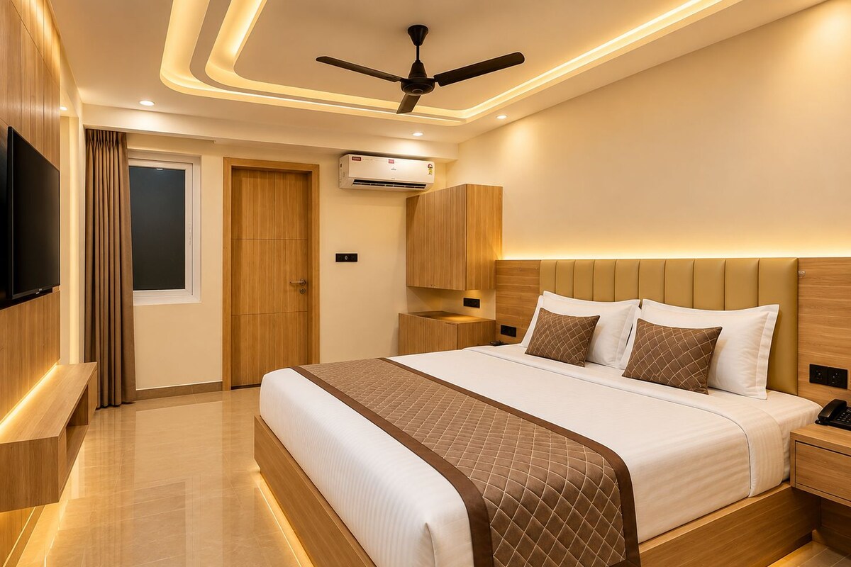 A modern hotel room with a large bed, a ceiling fan, an air conditioning unit, and a TV mounted on the wall.