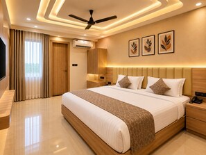 A modern hotel room with a large bed, a ceiling fan, an air conditioning unit, and artwork on the wall. - Hotel Akrati Inn Vrindavan (Mathura)