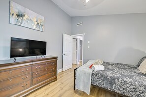 A bedroom with a bed, a dresser, a television, and a door leading to another room. - Centrally Located Charlotte Home w/ Patio & Yard! (Charlotte)