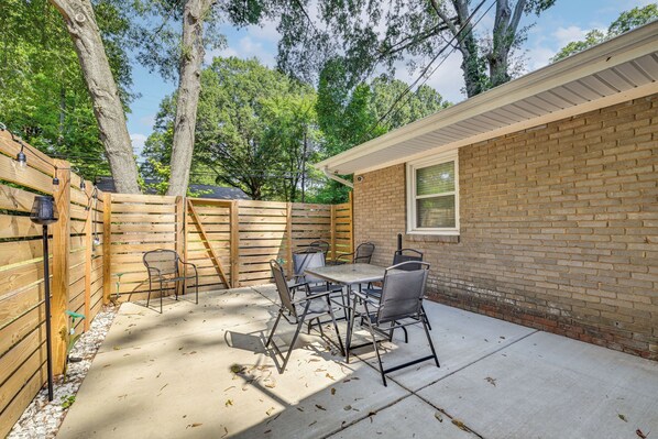 A patio area with a table and chairs, a wooden fence, and a brick building.
