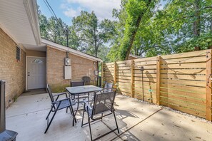 A patio area with a table and chairs, a brick wall, and a wooden fence. - Centrally Located Charlotte Home w/ Patio & Yard! (Charlotte)