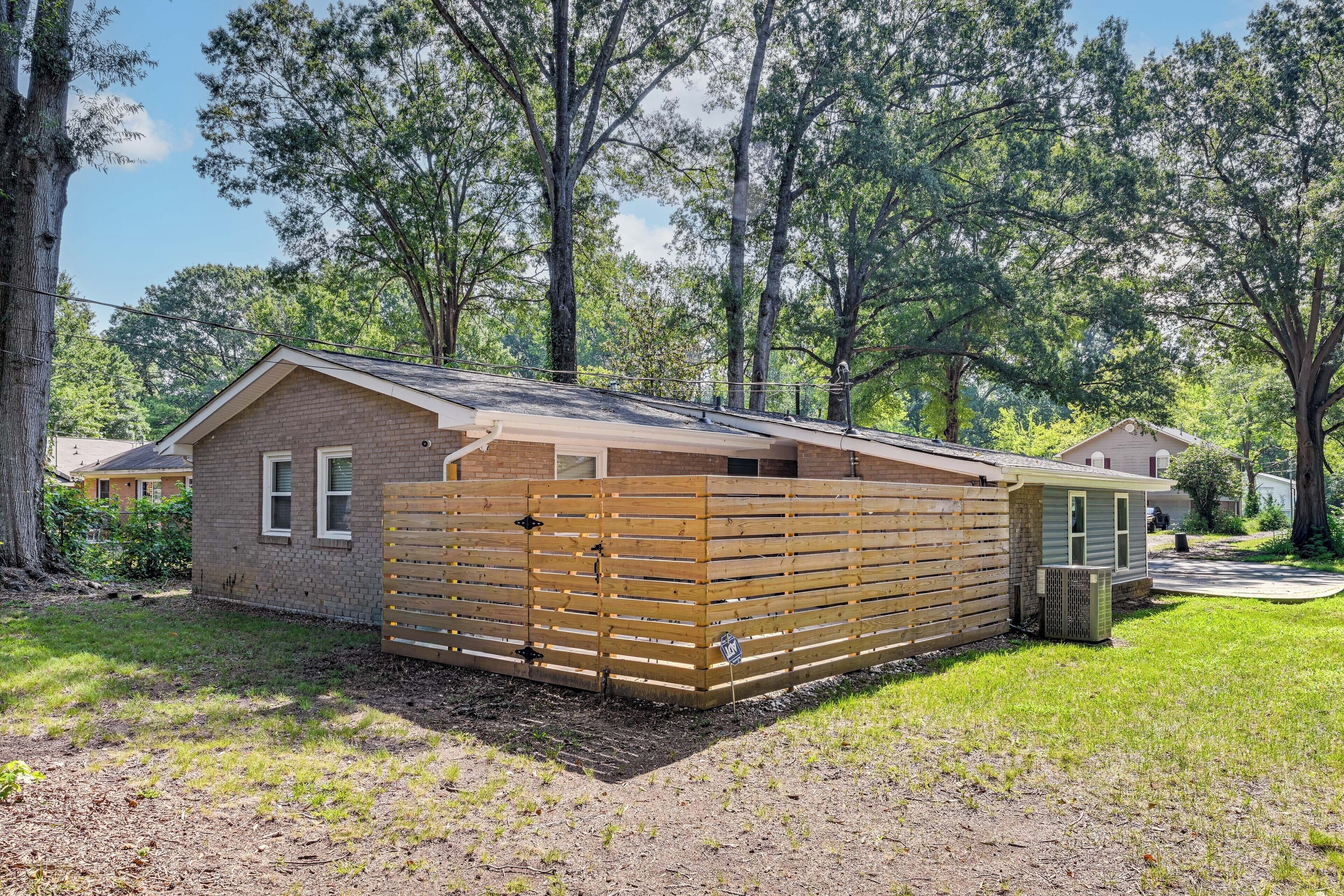 A single-story building with a sloped roof, a brick exterior, and a wooden fence.