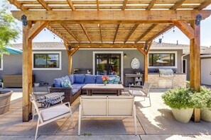 A covered patio with outdoor furniture, a grill, and a clock on the wall.