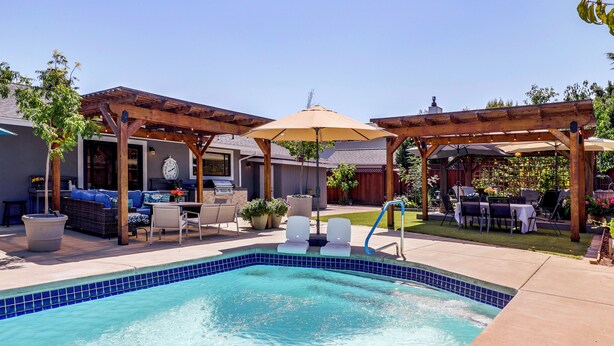 A backyard with a swimming pool, patio furniture, and a pergola with an umbrella. - Napa Extended Stay: Private Pool, Garage Parking! (Napa)