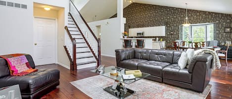 A spacious living room with a leather sofa, a glass coffee table, and a patterned rug.