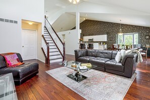 A spacious living room with a leather sofa, a glass coffee table, and a patterned rug.