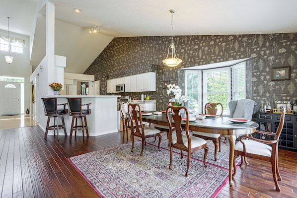 A dining area with a wooden table, chairs, and a patterned rug.