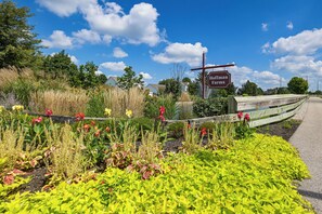 A sign for Hoffman Farms with a wooden fence and a variety of colorful flowers in the foreground. - Lake Views & Work Spaces: Quiet Hilliard Home! (Hilliard)