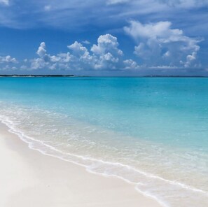 A beach with clear turquoise water and white sand.