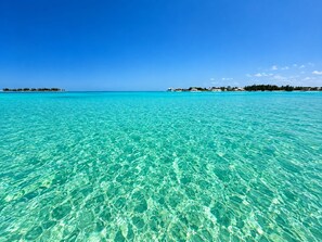 Un mar turquesa transparente con una costa lejana.