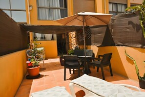 A patio area with a table, chairs, an umbrella, and a white lounge chair. - Vacation Home 'Romantic Gateway By The Sea' with Sea View, Private Terrace and Wi-Fi (Antigua)