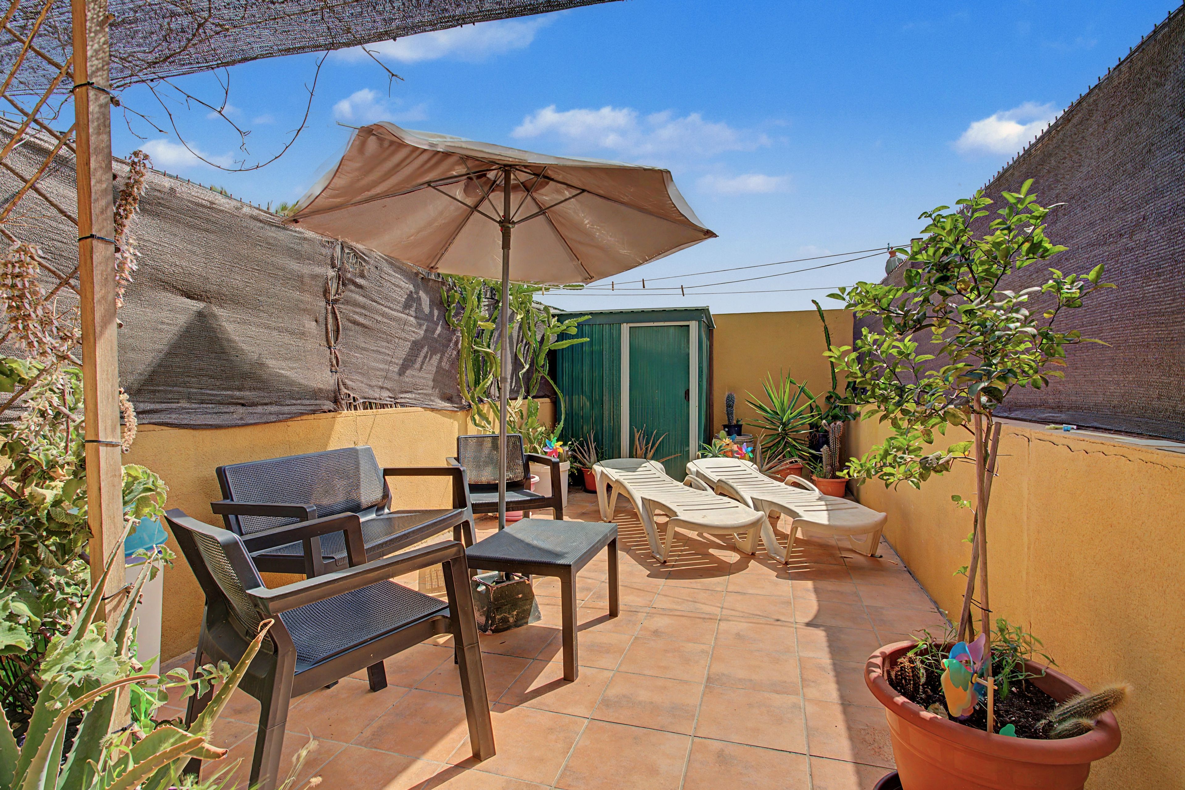 Un patio con muebles de exterior, una mesa, sillas y una planta en maceta.