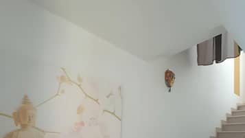 Een trap met een boeddhabeeld aan de muur en een decoratief masker.