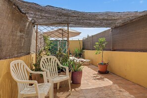 A patio with two white plastic chairs, a table, and potted plants. - Vacation Home 'Romantic Gateway By The Sea' with Sea View, Private Terrace and Wi-Fi (Antigua)