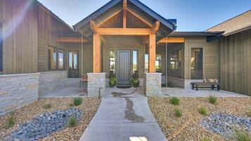A modern house with a stone facade, a covered porch, and a concrete pathway leading to the entrance.