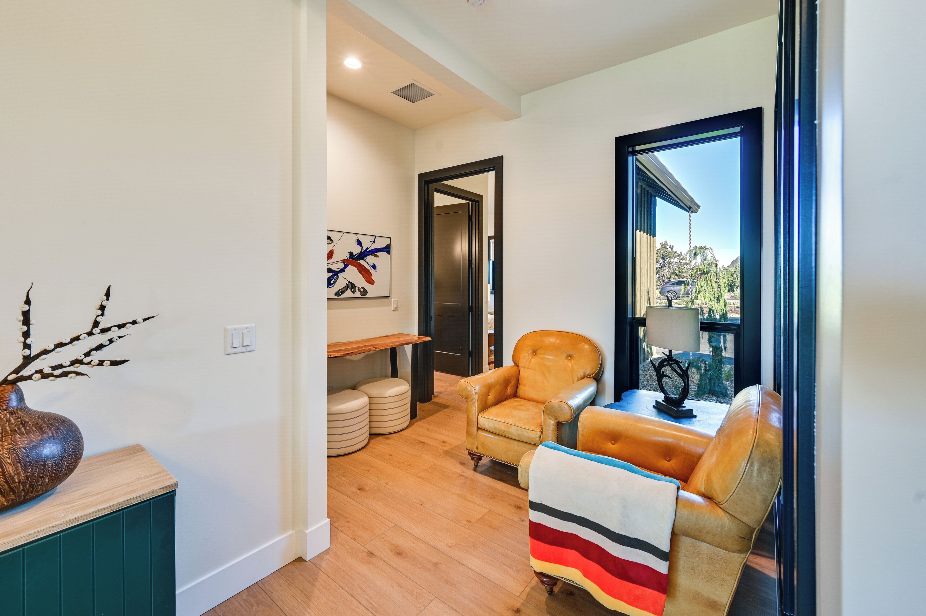 A modern living room with a sofa, a chair, a table, and a view through a window.