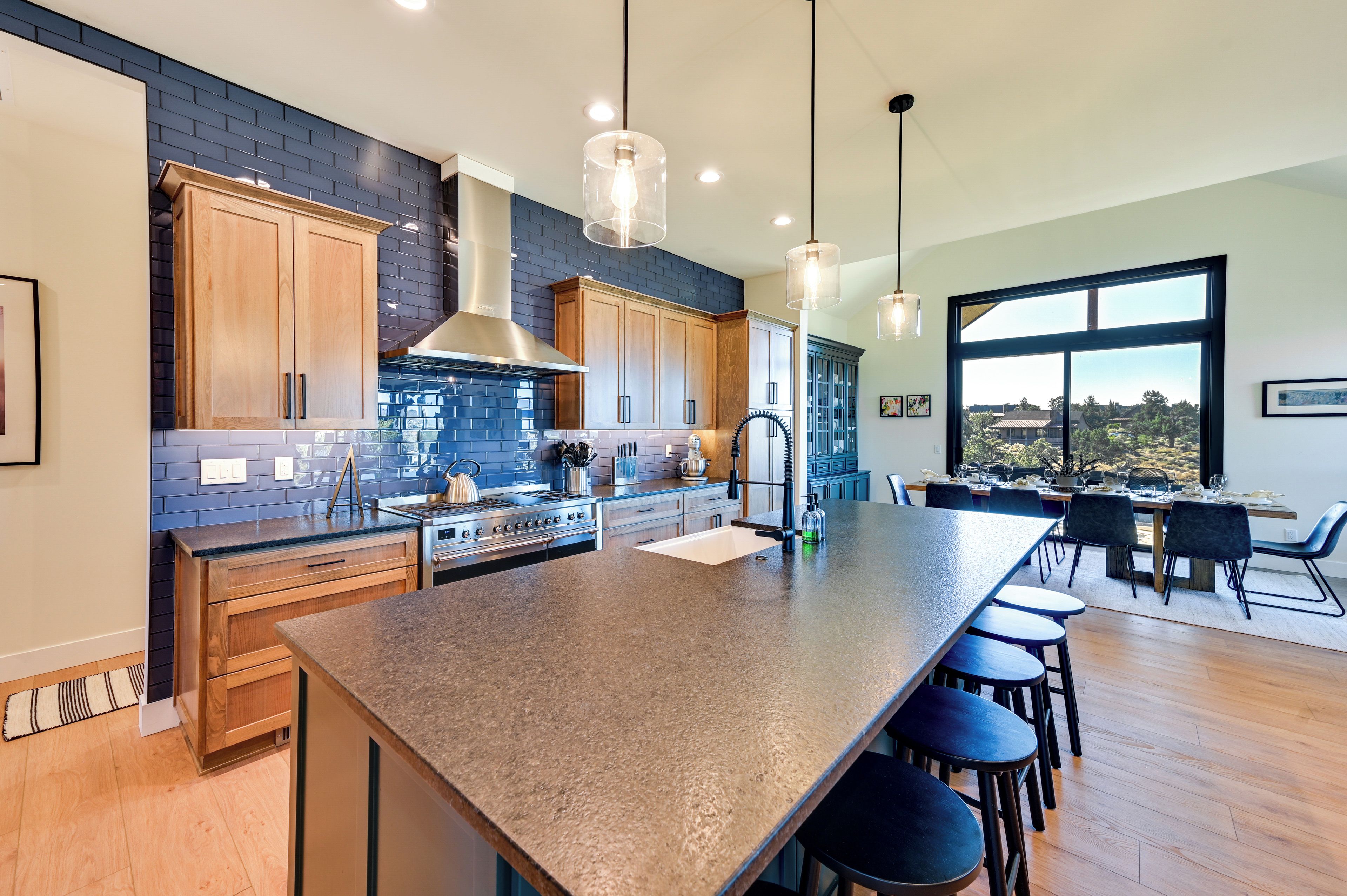 A modern kitchen with a large island, wooden cabinets, and a view of the outdoors.
