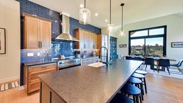 A modern kitchen with a large island, wooden cabinets, and a view of the outdoors.