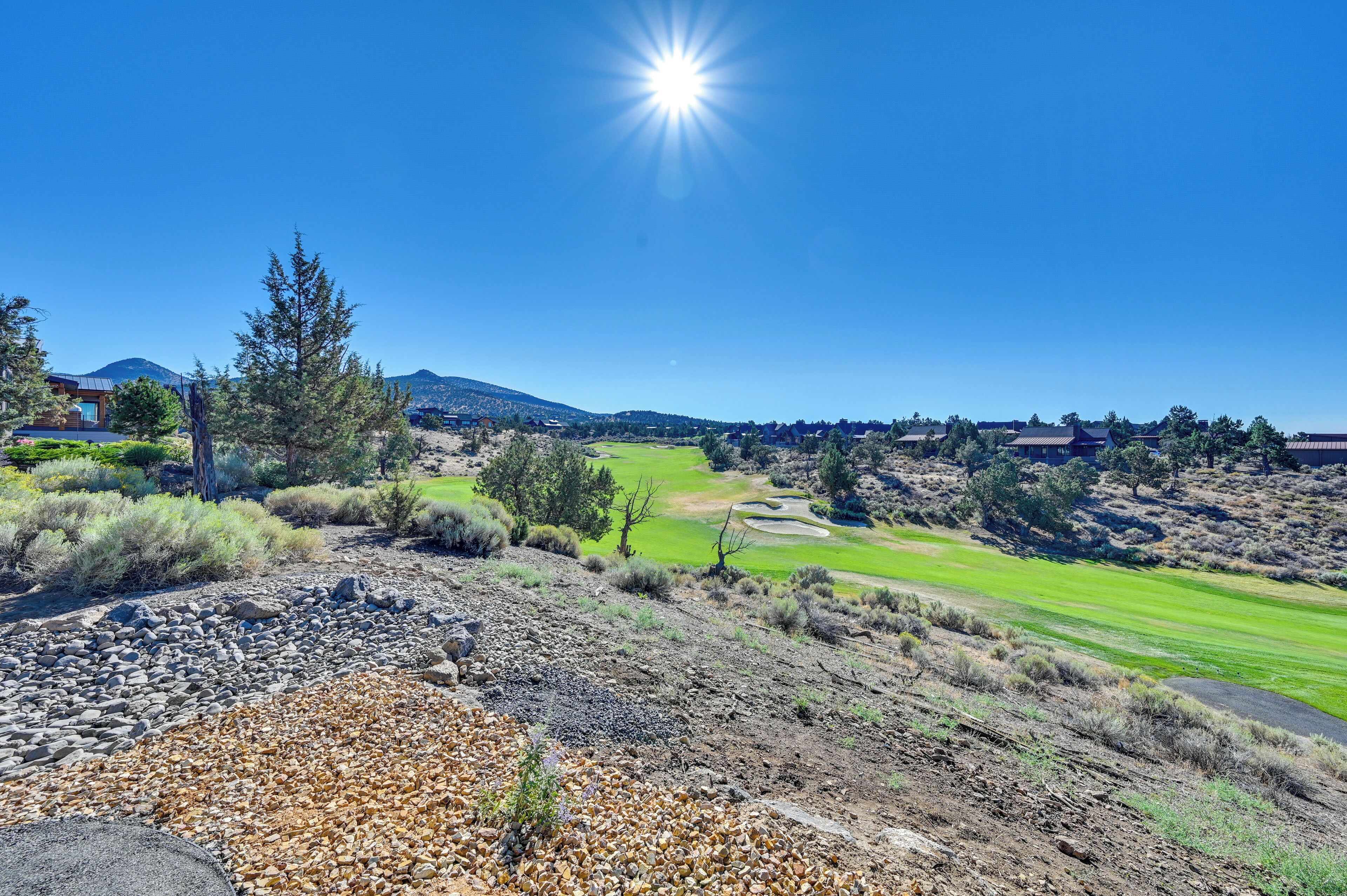 A golf course with a clear sky and distant mountains.