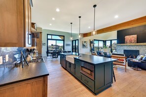 A modern kitchen with an island, dining area, and a fireplace.