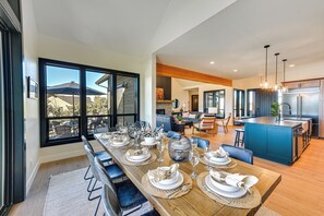 A modern kitchen with a large island, stainless steel appliances, and a dining area with a long table set for six.