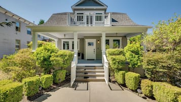 A two-story house with a front porch, a staircase leading to the entrance, and a well-maintained garden.