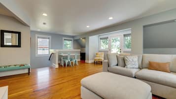 A spacious living area with a sofa, ottoman, and a dining table with chairs.