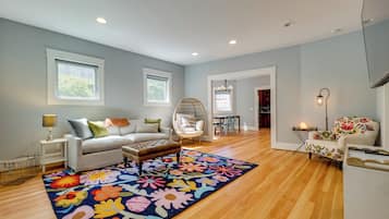A spacious living room with a sofa, a chair, a rug, and a dining area in the background.