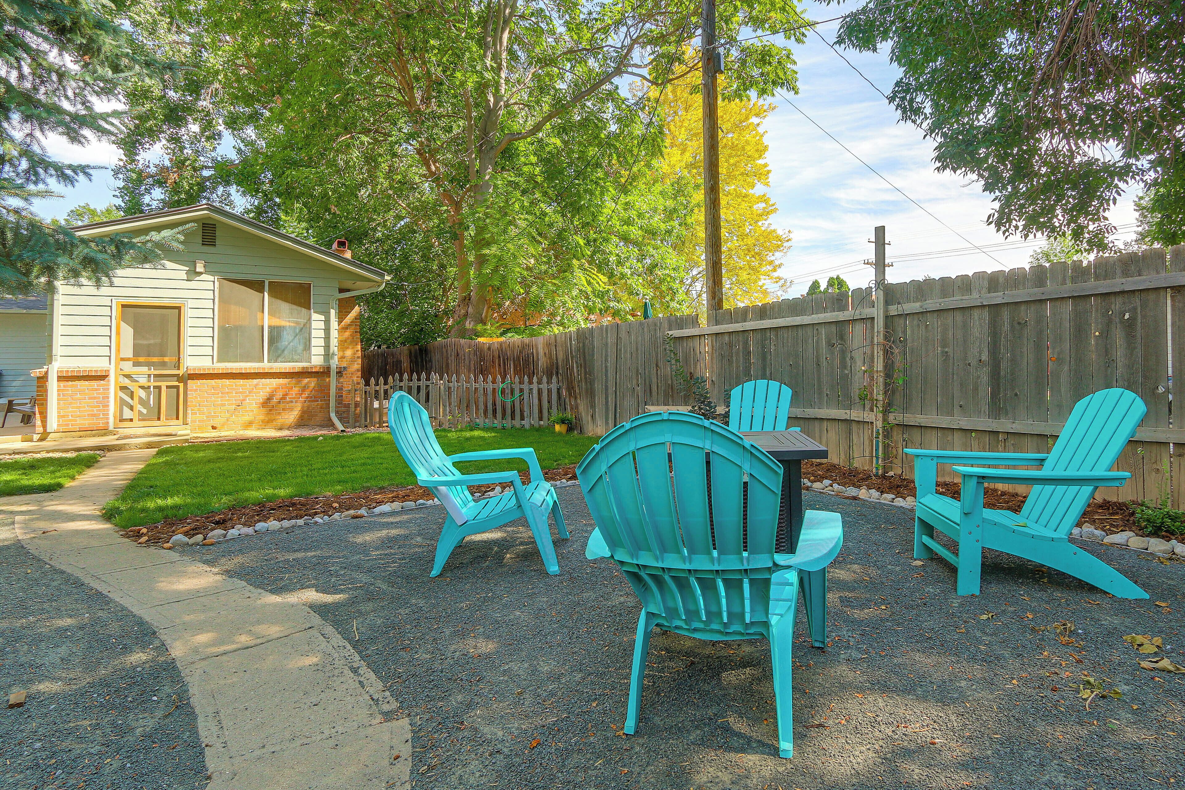 A backyard with a gravel patio, a wooden fence, and a small shed.