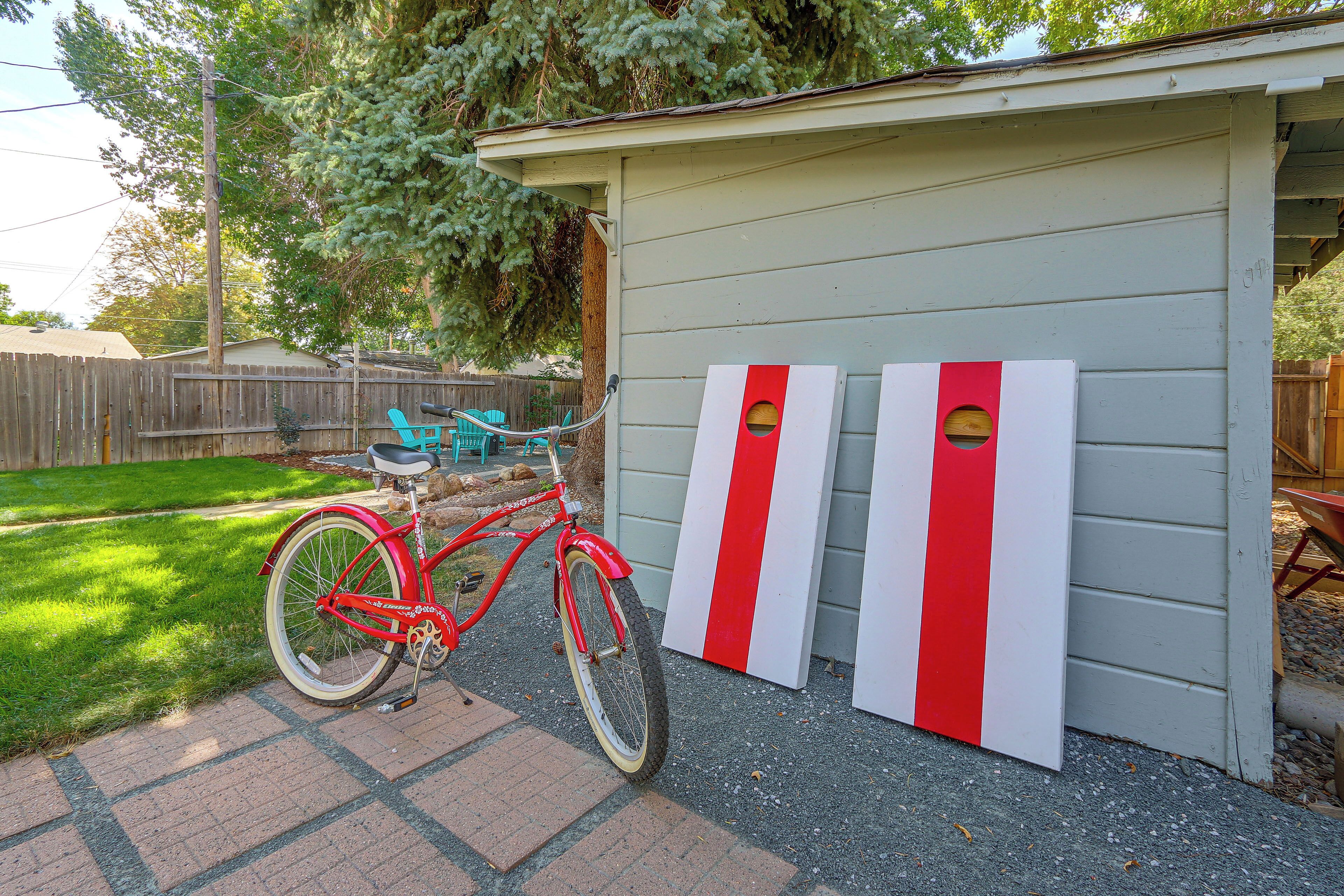 A red bicycle parked in front of a shed with two red and white striped objects.