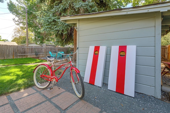 A red bicycle parked in front of a shed with two red and white striped objects.