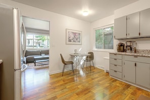 A compact kitchen with a dining area, wooden flooring, and a view of the outside.