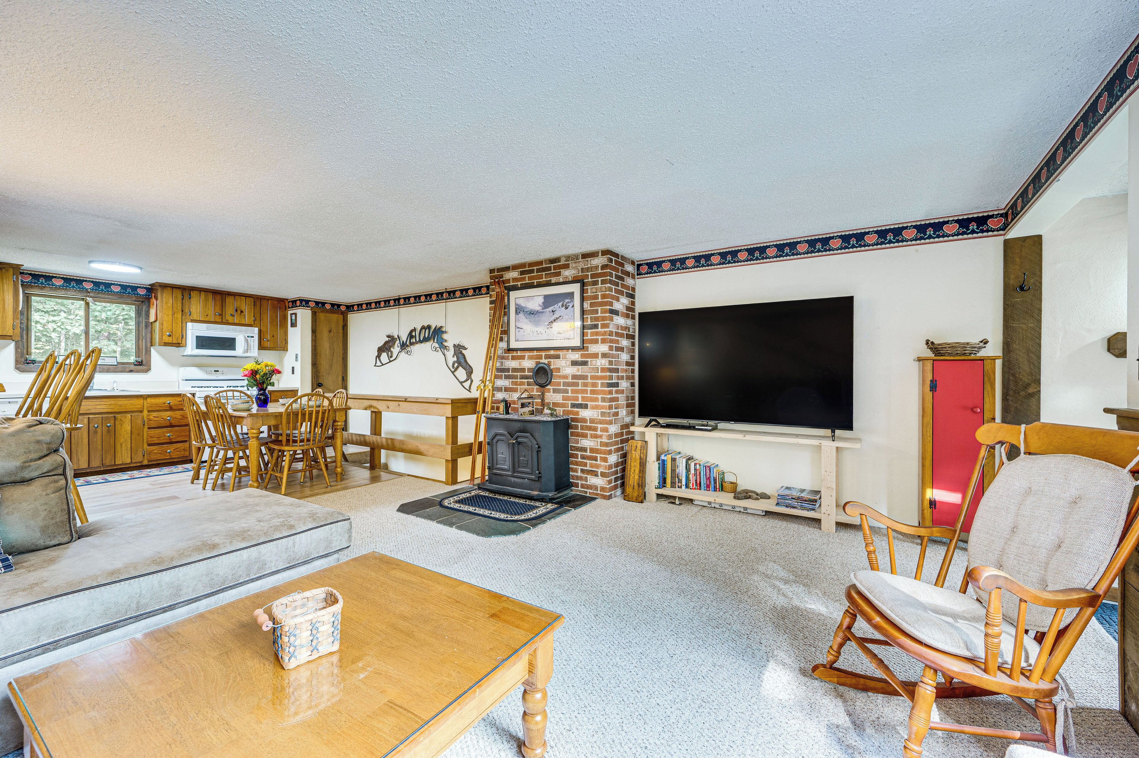 A cozy living room with a fireplace, a television, and a dining area with wooden furniture.
