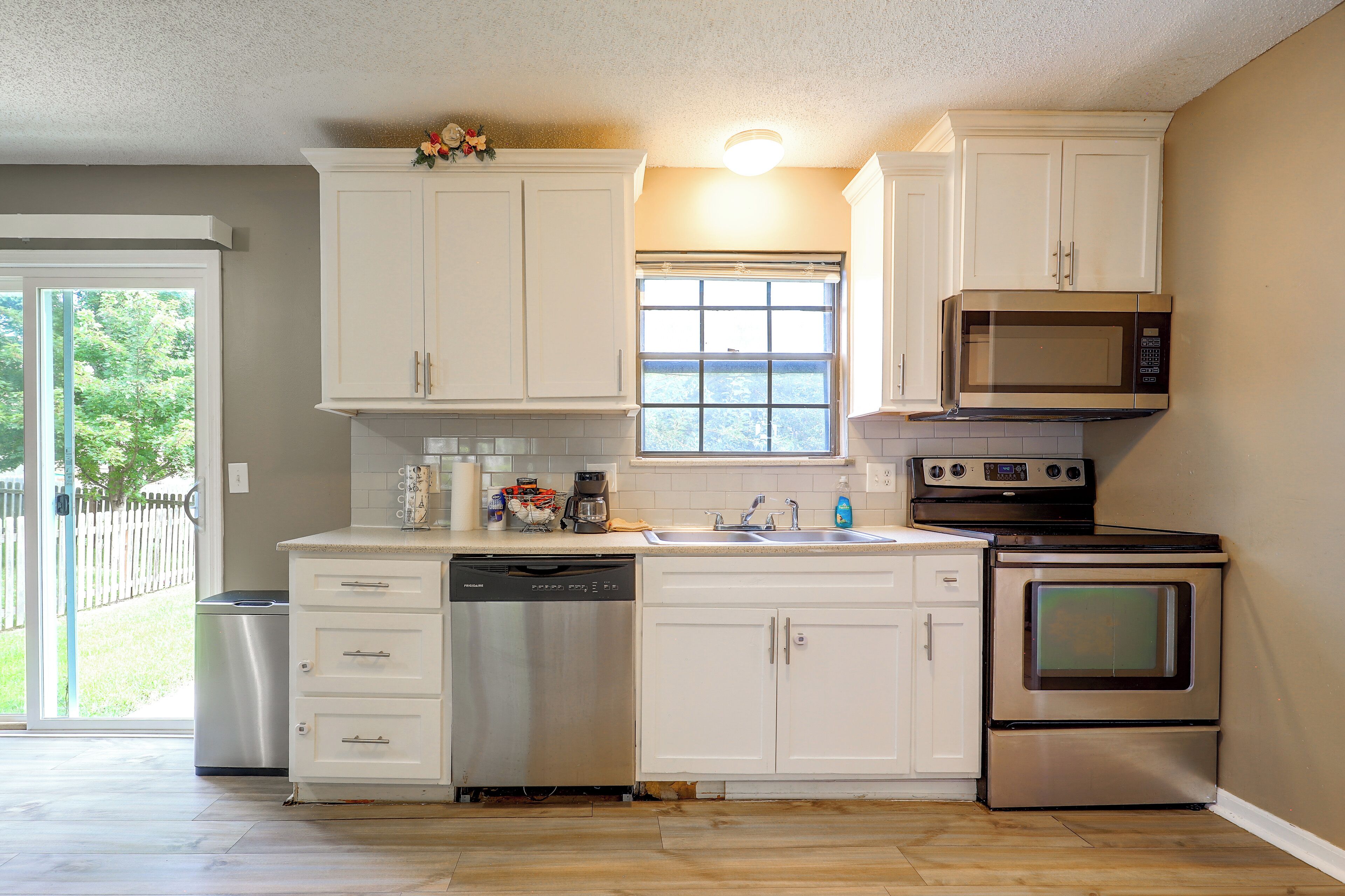 A kitchen with white cabinets, a dishwasher, a microwave, and an oven.