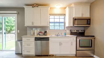 A kitchen with white cabinets, a dishwasher, a microwave, and an oven.