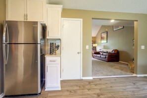 Una cocina con refrigerador de acero inoxidable, armarios blancos y piso de madera.