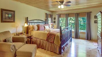 A bedroom with a wooden ceiling, a bed with a headboard, a chair, a dresser, and a window with curtains.
