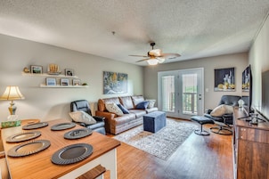 A spacious living room with a wooden dining table, leather sofas, and a ceiling fan.