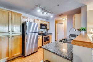 A modern kitchen with stainless steel appliances, wooden cabinets, granite countertops, and a built-in oven.