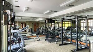 A gym with various exercise equipment, including treadmills and weight machines, and a large mirror reflecting the space. - Condo on Lake Hartwell 3 Mi to Clemson Stadium (Seneca)